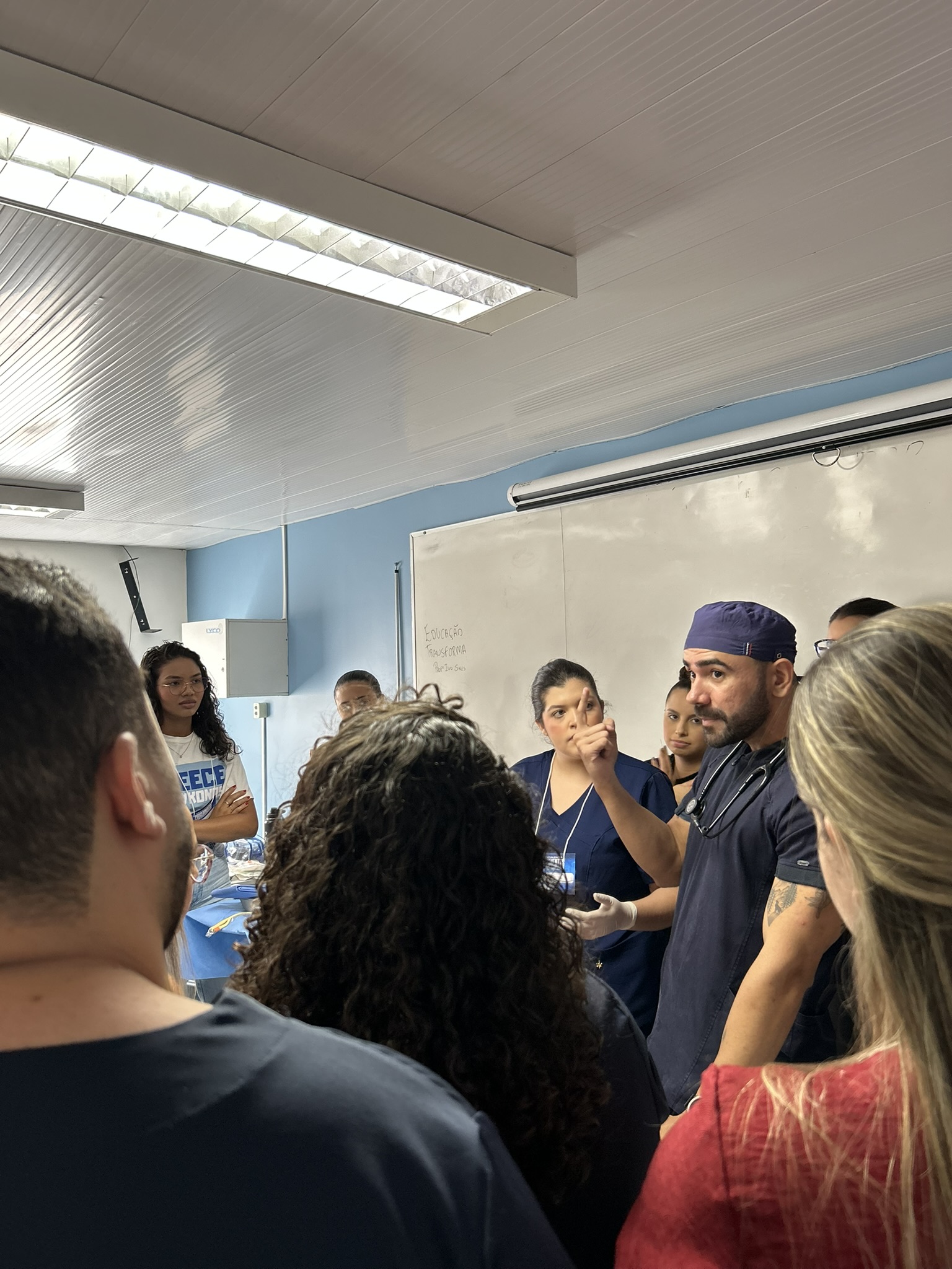 Professor e alunos concentrados em uma aula prática de enfermagem